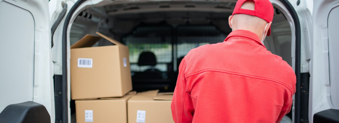 courier picking up parcels in back of van